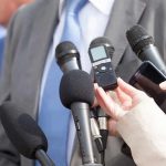 Microphones held toward a person in a suit