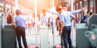 Security officers screen people at walk-through metal detectors