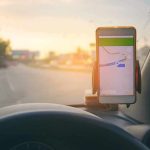 Google Maps Did THIS To Drivers, Without Their Consent smartphone with map app on car dashboard at sunset