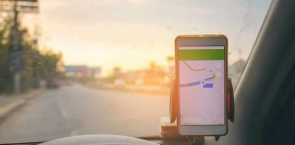 smartphone with map app on car dashboard at sunset