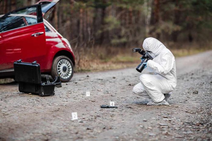 shutterstock_778440334-1 Forensic investigator photographing evidence near a red car on a rural road