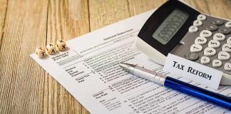 Tax form with calculator and pen on wooden desk