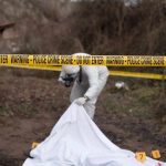 forensic investigator at outdoor crime scene behind caution tape