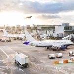 Runway Chaos: Passenger Hijacks Airport Tug Airplanes at airport gates during sunset with ground vehicles and jet bridges