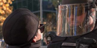 Anti-ICE Agitators Fuel Riot Mayhem protester faces police officer in riot gear