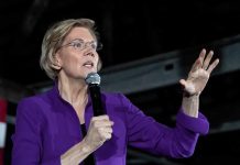 woman in purple jacket speaking into a microphone