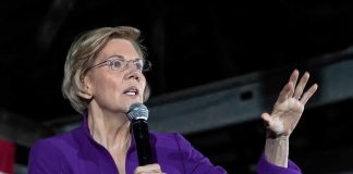 woman in purple jacket speaking into a microphone