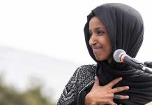 What FBI Found During Ilhan Omar Raid Will Stun You Ilhan Omar speaking at a microphone with hand on chest
