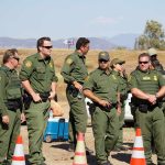 DHS Expose Cartel Plot to Abduct Border Patrol Agents Sid Fernandez and Bear Pascoe among uniformed officers standing near traffic cones outdoors