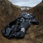 Body bags in a mass grave trench