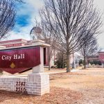 U.S City Council Meeting Opens With Hail Satan Prayer City Hall sign in front of a red-brick municipal building