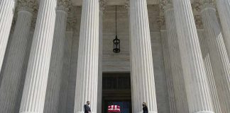 Flag-draped casket on courthouse steps between towering columns