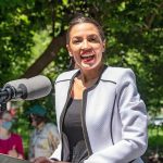 Woman speaking at an outdoor podium with microphone