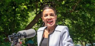 AOC in LGBTQ Church Sparks Firestorm Woman speaking at an outdoor podium with microphone
