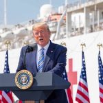 Trump Reveals MLB Icon to Receive Presidential Medal of Freedom Donald Trump speaking at a podium with American flags and a ship in the background